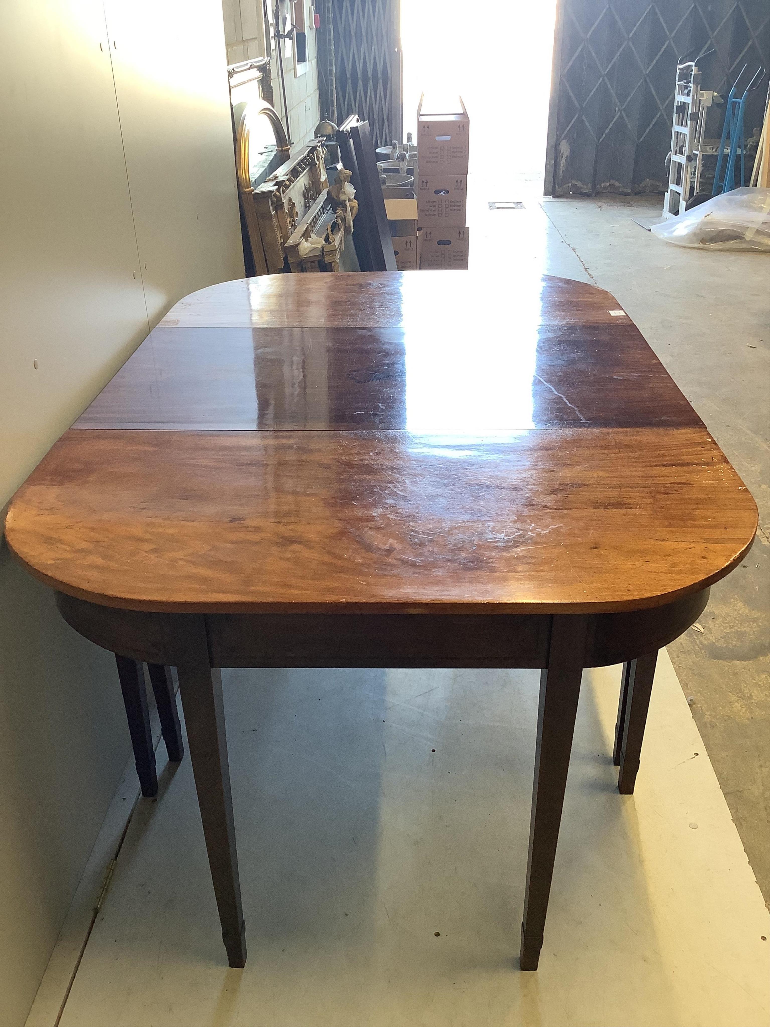 A George III mahogany D end extending dining table, width 162cm, (352cm extended, four spare leaves), depth 107cm, height 76cm. Condition - fair